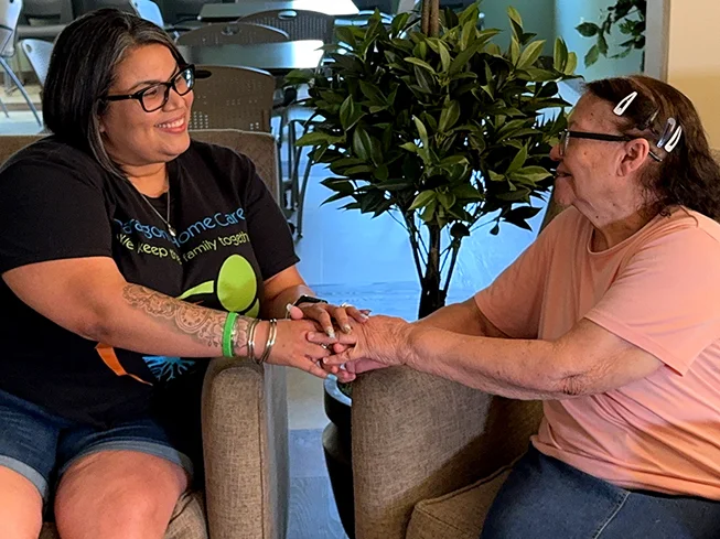 Home Care worker holding hands warmly with an elderly woman indoors