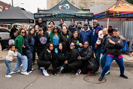 Large group of Paragon Home Care staff and community members posing together at an outdoor outreach event