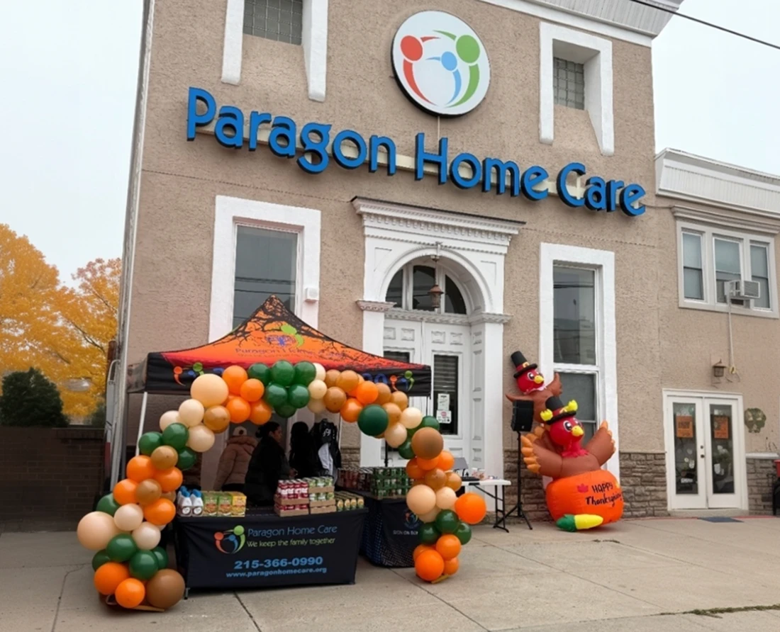 Paragon Home Care office exterior decorated with a Thanksgiving balloon arch, branded booth table, and an inflatable turkey for a holiday community event